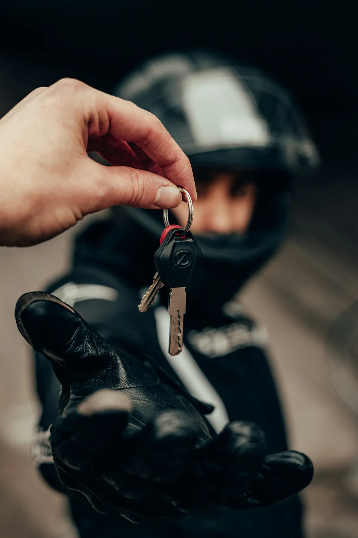 Entrega de las llaves de una moto a un motorista con casco y guantes